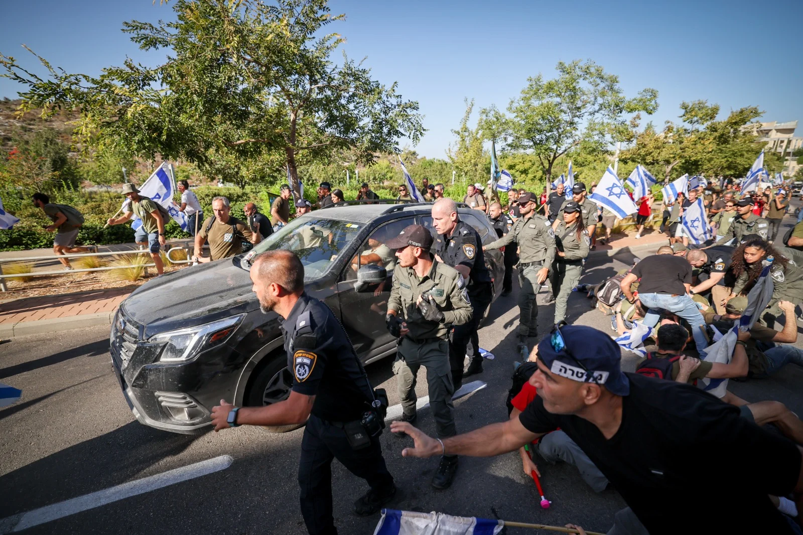 רכבו של לוין נוסע בין המפגינים תחת אבטחה כבדה